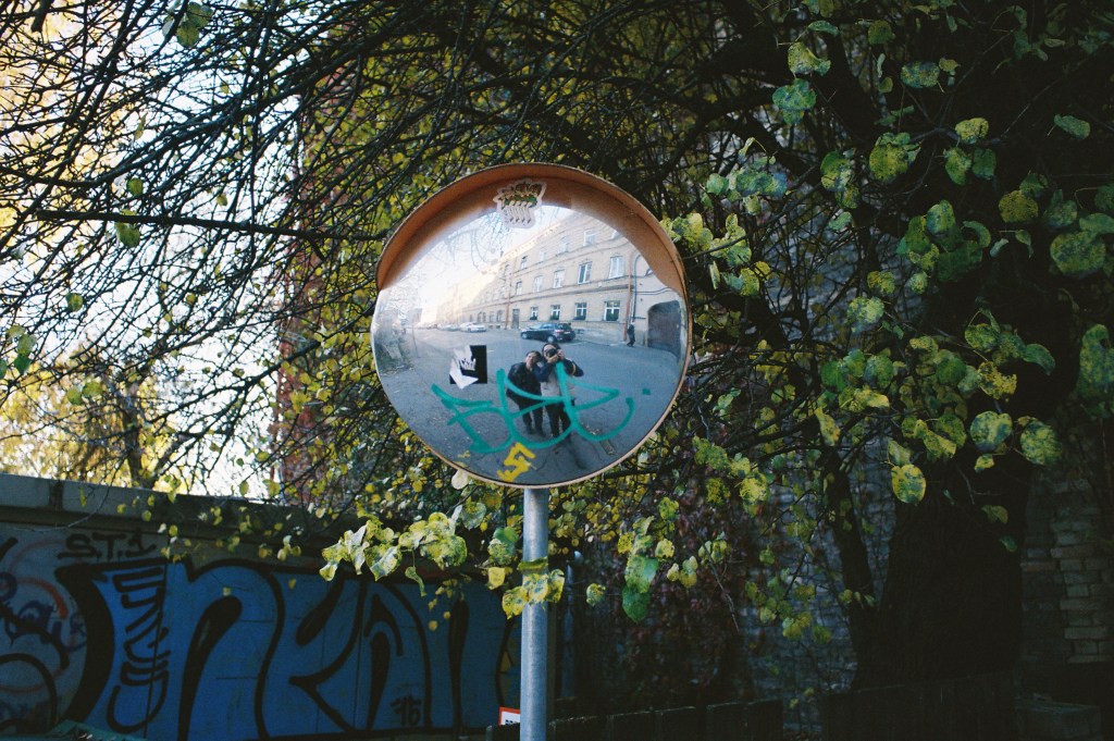 Two people taking selfie in convex security mirror